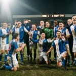 Soccer team celebrating victory on stadium pitch after winning football match
